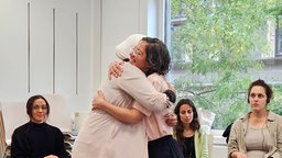 Zwei Frauen umarmen sich in der Dialoggruppe 