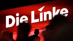 Delegierte sitzen auf dem Bundesparteitag unter dem Logo der Partei "Die Linke". 