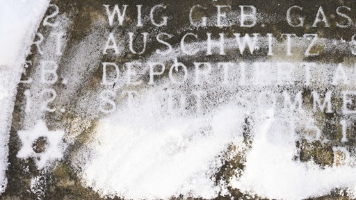 Schnee liegt auf der Schrifttafel des Holocaust-Mahnmals am Opernplatz in Hannover. Erkennbar sind die Worte "Auschwitz" und "deportiert", sowie ein Judenstern.