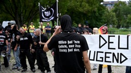Teilnehmer einer rechtsextremen Demonstration am 26.07.2025 in Berlin. Auf einem T-shirt ist in Fraktuschrift zu lesen "Alles hat einen Haken, nur das Kreuz hat vier".
