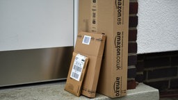Päckchen des Online-Versandhändlers Amazon stehen vor einer Haustür 