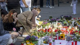 Menschen legen in der Nähe des Tatorts der Messerattacke auf dem Solinger Stadtfest Blumen und Kerzen zum Gedenken der Opfer nieder. 
