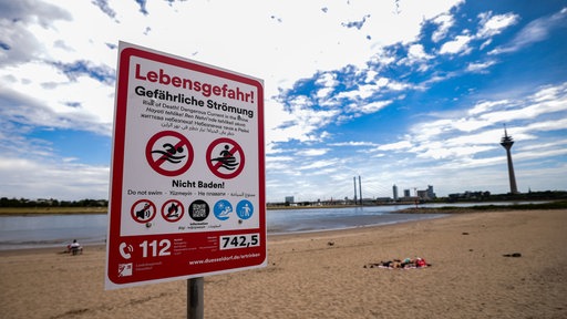 Ein Hinweisschild am Paradiesstand in Düsseldorf weist auf die Gefahren beim Schwimmen im Rhein hin