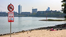 Ein Schild weißt auf das Badeverbot in Düsseldorf am Rhein hin.