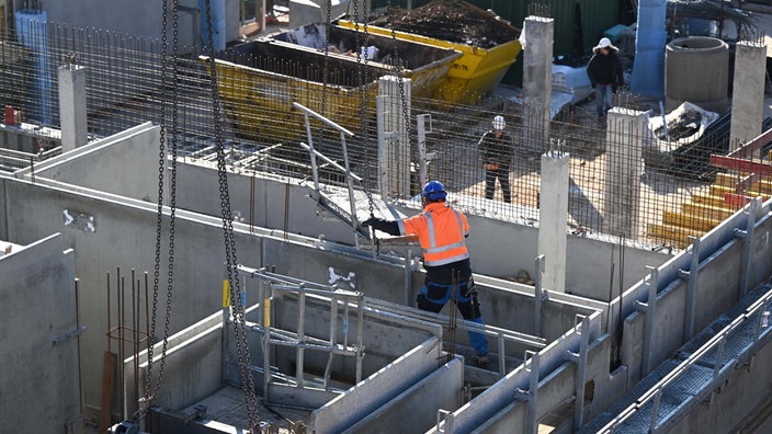 Auf einer Baustelle für Wohnungen und Sozialwohnungen arbeiten Bauarbeiter am Rohbau.