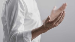 Symbolbild: Ein Mensch in einem weißen Hemd hält die Hände mit den Handflächen nach oben vor sich.