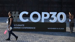 Ein Mensch läuft am Schriftzug der Weltklimakonferenz COP30 vorbei.