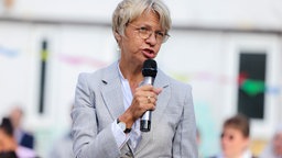 NRW-Schulministerin Dorothee Feller (CDU) spricht auf einer Verantstaltung im Freien in ein Mikrofon