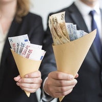 Eine Frau und ein Mann halten unterschiedlich große Tütchen mit Geld hoch