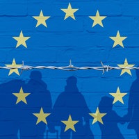 Europaflagge auf einer Mauer und Umrisse von Asylsuchenden hinter einem Stacheldraht. Symbolbild Asylrechtsreform