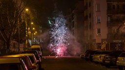 Symbolbild: Eine Feuerwerk zwischen Autos und Mehrfamilienhäusern auf einer Straße in Leipzig (2025).