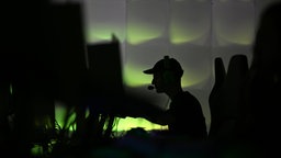 Ein Gamer sitzt in einem dämmrigen, grünlich beleuchteten Raum an einem von mehreren Computern. Aufgenommen auf der "Caggtus"-Messe in Leipzig.