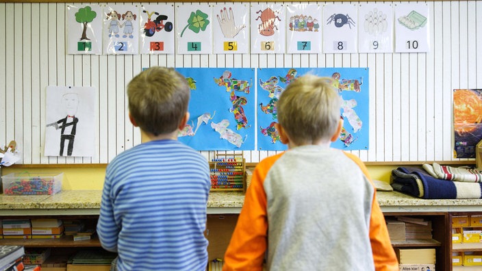 Symbolbild: Rückansicht von zwei Grundschulkindern, die auf Lerntafeln schauen (2014).