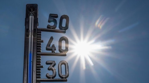 Ein Thermometer zeigt heiße Temperaturen an, im Hintergrund die gleißende Sonne