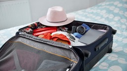 Symbolbild: Ein für einen Sommerurlaub gepackter, offener Reisekoffer.