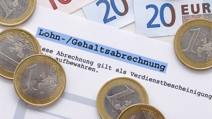 Lohn- / Gehaltsabrechnung Symbolfoto mit Gelscheinen und Münzen
