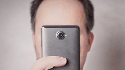 Ein Mann fotografiert mit einem Smartphone. Symbolbild