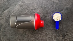 Symbolbild: Proteinpulver neben einer Trinkflasche