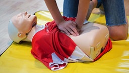 Symbolbild: Ein Mensch trainiert eine Herzdruckmassage an einer speziellen Übungspuppe.