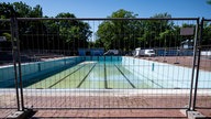 Symbolbild: Bauzaun vor dem Schwimmbecken eines Freibades.
