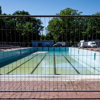 Symbolbild: Bauzaun vor dem Schwimmbecken eines Freibades.