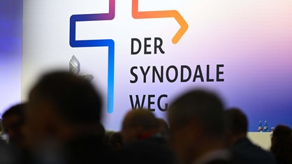 Teilnehmer der Synodalversammlung sitzen vor dem Schriftzug "Der Synodale Weg". 