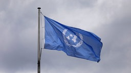 UN-Flagge weht im bewölkten Himmel. 
