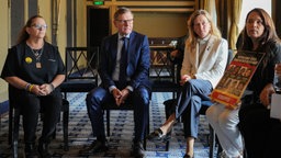 Außenminister Wadephul (CDU) und SPD-Außenpolitikerin Siemtje Möller (weiße Jacke) sitzen am 01.08.25 in der Bibliothek des Delegationshotels mit Angehörigen von Hamas-Geiseln