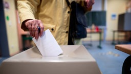 Symbolbild: Eine Person wirft in einem Wahllokal ihren Wahlzettel in die Wahlurne.