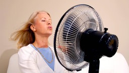 Eine Frau lässt sich von einem Ventilator "abkühlen". Symbolbild: Wechseljahre, Hitzewallungen