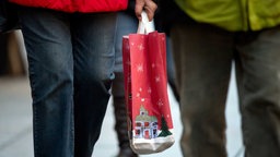 Symbolbild: Mensch trägt Papiertüte mit Weihnachtsmotiv