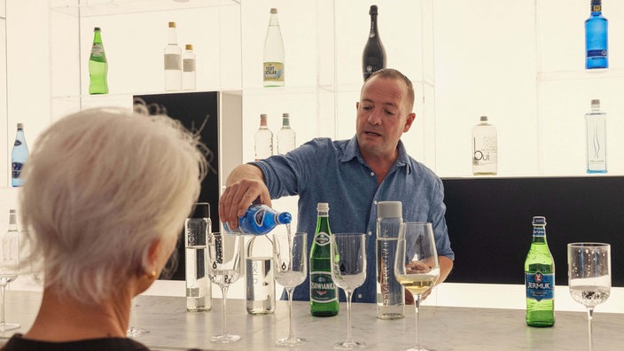 Wassersommelier Nico Pieterse und eine Besucherin beim Verkosten seiner Wasser-Sorten. 