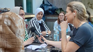 Ein Foto von einer Intervierwin, die Migrantinnen interviewt 