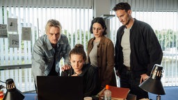  Adam Schürk (Daniel Sträßer), Pia Heinrich (Ines Marie Westernströer), Esther Baumann (Brigitte Urhausen) und Leo Hölzer (Vladimir Burlakov) schauen auf ein Überwachungsvideo.