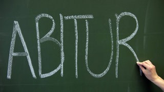 Auf eine grüne Schultafel wurde das Wort "Abitur" mit weißer Kreide geschrieben.