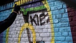 Ein Graffitikünstler übersprüht Nazi-Schmierereien an einem Haus im Stadtteil Dorstfeld