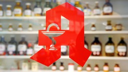 Rotes Apothekensymbol am Fenster einer Apotheke.
