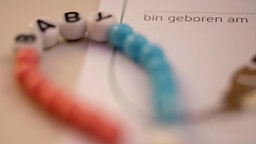 In einer Klinik für Frauenheilkunde und Geburtshilfe liegt ein neues Kettchen für ein Baby bereit.