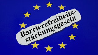 Auf blauem Hintergrund wird mit gelben Sternen die Flagge der Europäischen Union angedeutet – mittig davon befindet sich ein Stück Paoier mit der Aufschrift "Barrierefreiheitsstärkungsgesetz".