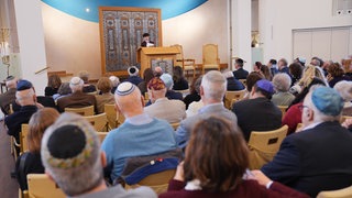 Männer mit Kippa und Frauen sitzen in der Belsize Square Synagoge im Stadtteil Belsize Park in London bei einer Veranstaltung der "Association of Jewish Refugees" (AJR) am 20.01.2026