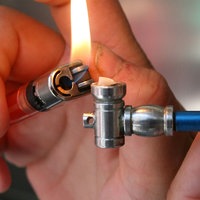 Nahaufnahme auf Hände die mit einem Feuerzeug eine Crack-Pfeife anzünden.