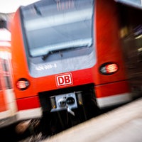 Eine rote Regionalbahn der Deutschen Bahn fährt in einen Bahnhof ein, vom Bahnsteig aus fotografiert.