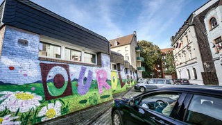 In einem Straßenzug in Dortmund-Dorstfeld ist über mehrere Häuser der Satz "Our colours are beautiful" gesprüht