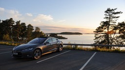 Ein Tesla-Elektroauto steht auf einem Parkplatz an der Küste in Norwegen. 