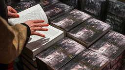 Eine Frau hat das Buch "Alchemised" von Autorin SenLinYu  aufgeschlagen