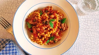 Ein Teller mit Pasta, Tomate und Thunfisch.