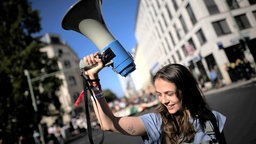  Symbolbild: Demonstrantin mit Megafon.
