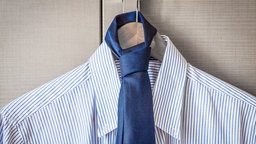 Männerhemd und blaue Kravatte auf einem Kleiderbügel