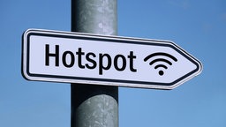 in weißes Schild am Pfahl einer Straßenlaterne mit der Aufschrift "Hot Spot" weist nach rechts.