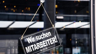 Auf einem Schild steht: "Wir suchen Mitarbeiter!"